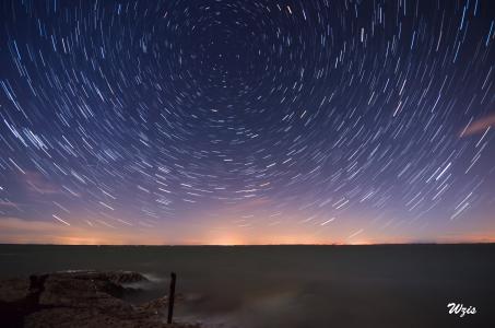 <p>Avez vous déjà pris le temps de contempler un ciel magnifiquement étoilé ? Repérez une constellation et revenez un quart d'heure plus tard et si vous êtes consciencieux vous aurez l'impression que celle ci s'est déplacée :) et bien cette technique a pour but d'immortaliser cette impression de déplacement et met donc en évidence la rotation de notre belle planète !</p><p>C'est une de mes techniques préférée.. il faut trouver dans un premier temps un endroit où le ciel subit le moins possible la pollution lumineuse des villes environnantes.</p><h3>"Ça tombe bien ! J'habite en ville et à 3 km de chez moi il y a un endroit sans lampadaires"</h3><p>Soyez un peu plus exigeant :) ce n'est pas aussi simple la lumière se diffuse dans le ciel et ce n'est pas à 3 km loin des lampadaires que vous verrez plus d'étoiles !</p><p>Heureusement, il existe des <a href="http://avex-asso.org/" target="_blank">outils</a>, des <a href="http://avex-asso.org/dossiers/pl/europe-2016/google-map-fausse-couleur/index.html" target="_blank">cartes</a> qui vous permettent de connaître le taux de pollution lumineuse à partir d'adresses. Si vous habitez en ville, il ne sera pas simple d'en trouver, mais plus vous prendrez le soin de sélectionner votre endroit avec un taux de pollution lumineuse bas, plus vous verrez des étoiles et moins vous aurez une impression de jour sur l'horizon de vos photos et donc ... votre filé sera plus joli.</p><p>Une fois sur place, faite des tests pour trouver le bon réglage : le compromis entre la vitesse, l'ouverture et les ISOs.</p><p>Eviter des ISOs trop élevés pour le bruit  mais aussi des ISOs trop bas car si votre ciel est de bonne qualité avec 100 ISO comptez plusieurs minutes par photo et c'est long même avec un objectif ultra lumineux :).</p><p>J'ai testé et je ne recommande pas, il y a moins de bruit mais si il y a un peu de vent votre paysage ne sera pas complètement net et le peu de bruit que vous aurez se résorbera assez bien avec vos logiciels habituels de développement photo.</p><p><strong>Attention il est important de :
- faire la mise au point sur l'infini et donc de désactiver l'autofocus,
- désactiver la stabilisation de l'objectif,
- Se mettre en mode manuel pour que vos réglages ne se changent pas entre chaque photo</strong></p><p>Une fois tous les réglages prêt, sortez votre boussole et faites en sorte que le nord soit dans votre champ de vison car l'étoile polaire qui si trouve et la seule à ne pas "bouger" et donc les filés se feront autour d'elle.</p><p>Il suffit ensuite de poser l'appareil sur le trépied, de configurer l'intervallomètre ou d'utiliser directement une télécommande filaire basique et de faire un dernier test.</p><p>Hop la série de photo est lancée :). Plus vous serez courageux en étant patient, plus votre filé sera conséquent, essayez de rester le plus de temps possible pour avoir un maximum de photos.</p><p>Grâce à cette technique si vous vous débrouillez bien, à la fin de votre soirée, vous serez fatigué mais vous aurez en votre possession un beau filé d'étoiles, un futur <a href="techniques#vortex">vortex</a> et un superbe time-lapse. :)</p><p>Une fois rentré chez vous retraitez l'ensemble de vos photos si vous en ressentez le besoin et assemblez les grâce à un logiciel spécialisé comme Starmax. Ces logiciels sont vraiment simples d'utilisation et vous trouverez beaucoup d'indications sur Internet</p>